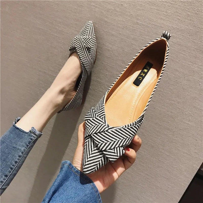 Women's black pointed toe low heel flats with a shallow mouth design on a plain background