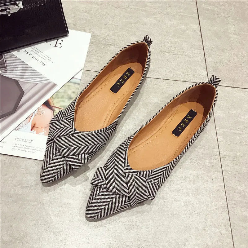 Women's black pointed toe low heel flats with a shallow mouth design on a plain background