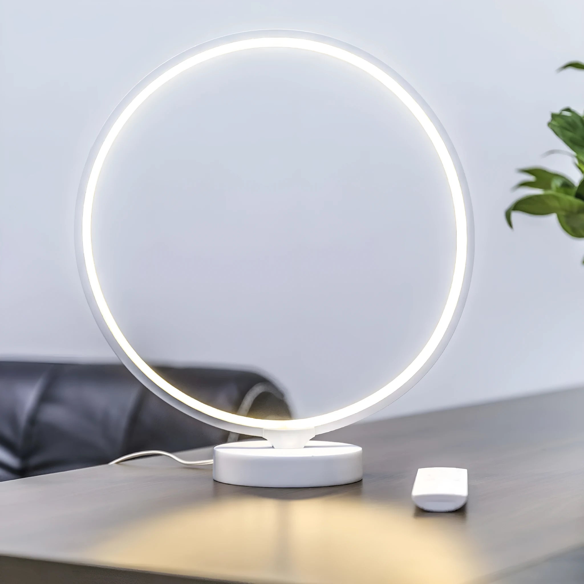 White aluminium and silicone full moon mood lamp with remote control on a table.