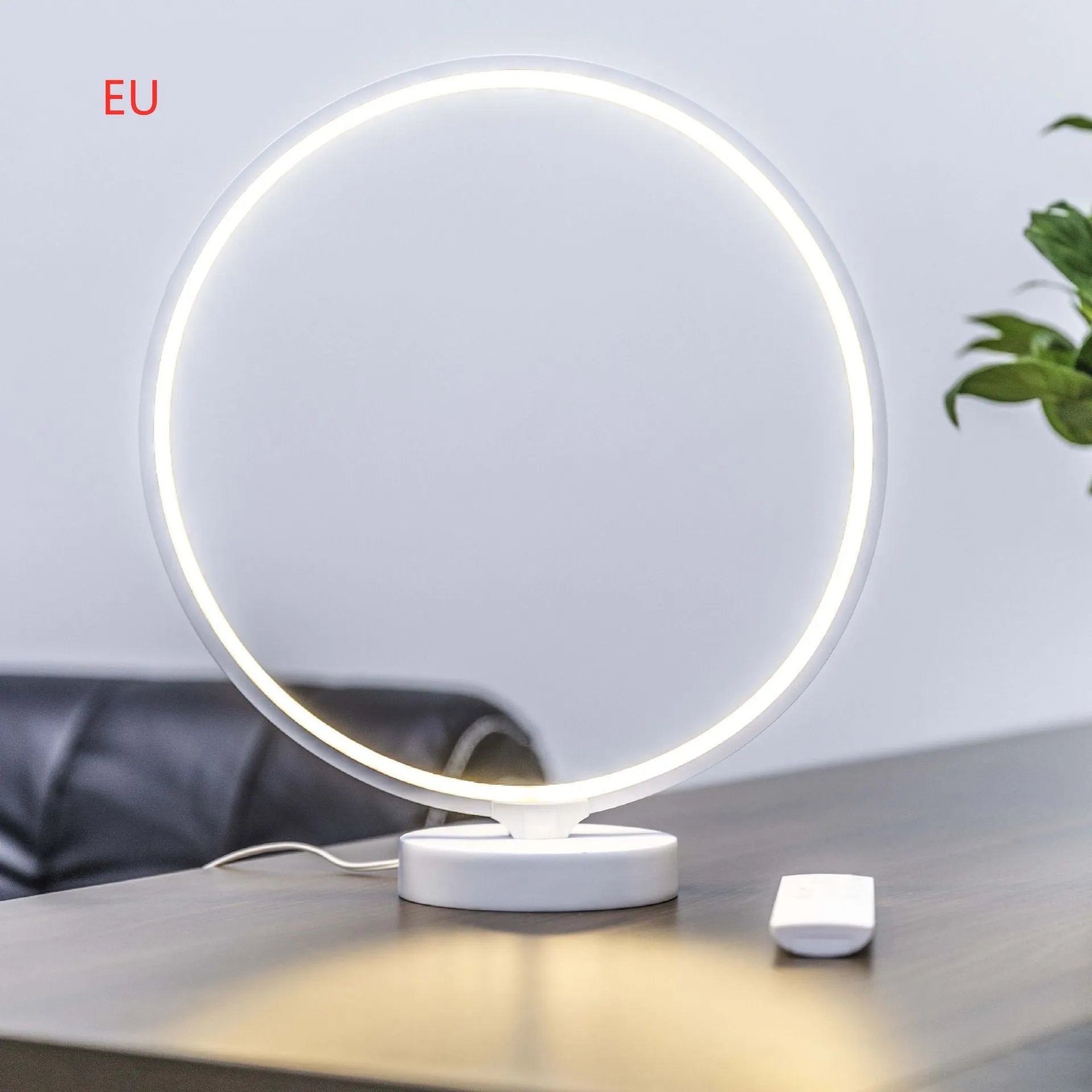 White aluminium and silicone full moon mood lamp with remote control on a table.