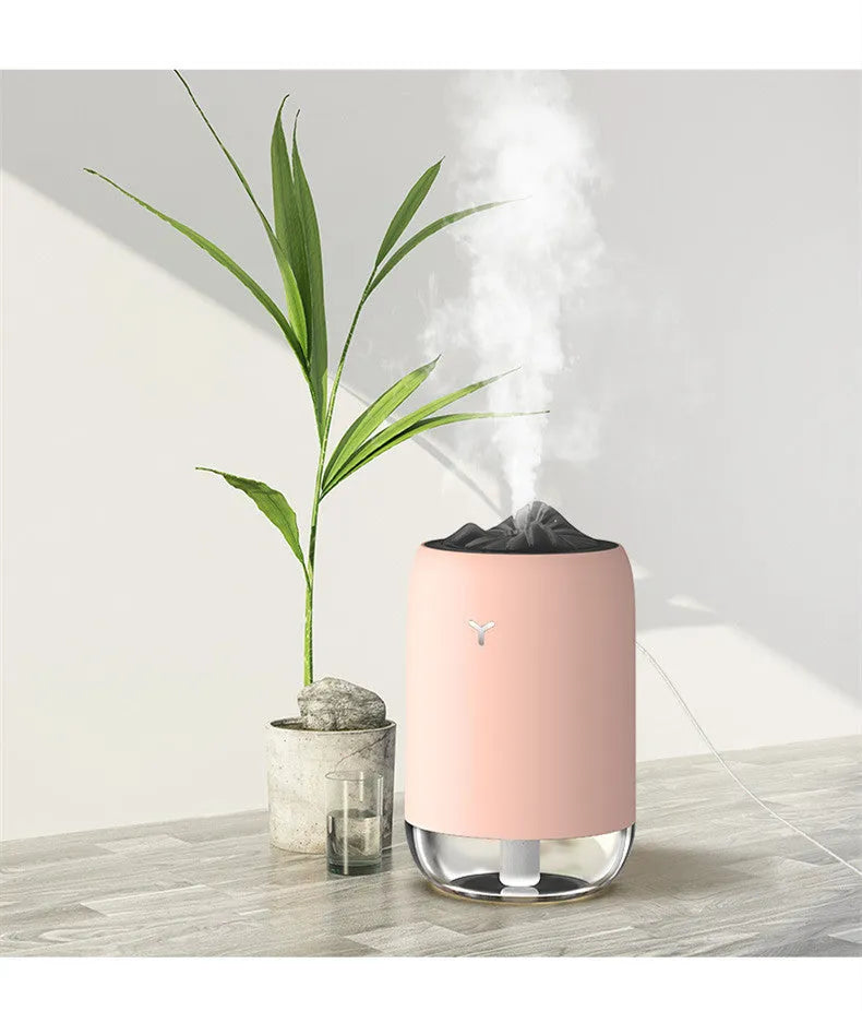 White columnar Magic Flame ultrasonic humidifier with USB cable and water tank on a wooden desk.