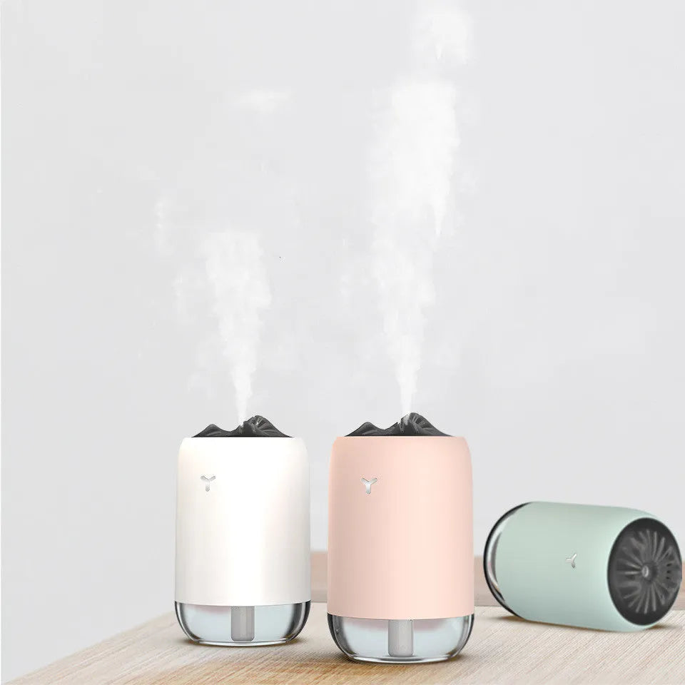 White columnar Magic Flame ultrasonic humidifier with USB cable and water tank on a wooden desk.