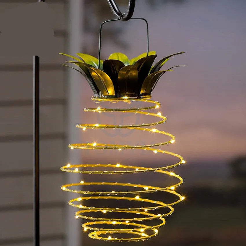 Outdoor waterproof green pineapple solar path light with 20 warm white LEDs and metal frame on a garden table