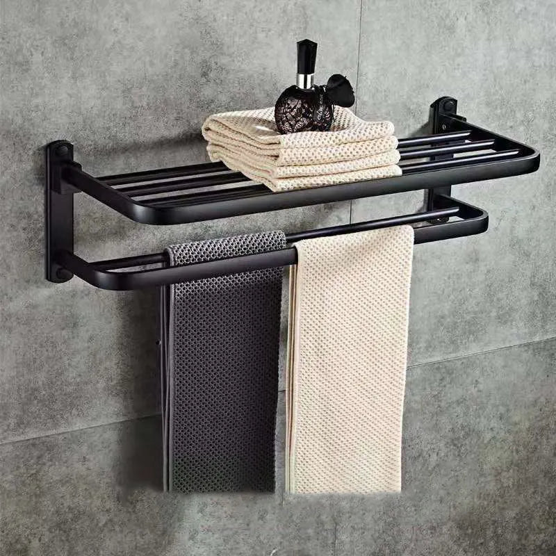 Silver aluminium double-layer folding towel rack with perforated shelf mounted on a bathroom wall.