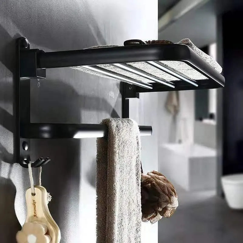 Silver aluminium double-layer folding towel rack with perforated shelf mounted on a bathroom wall.