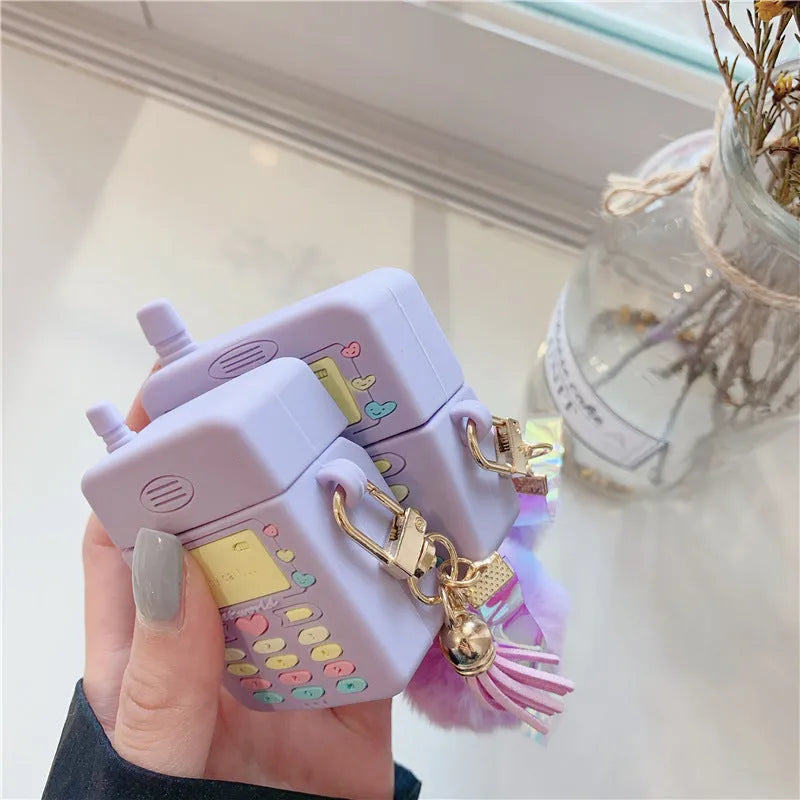 Purple silicone Apple AirPods protective case with attached fur ball pendant on white background