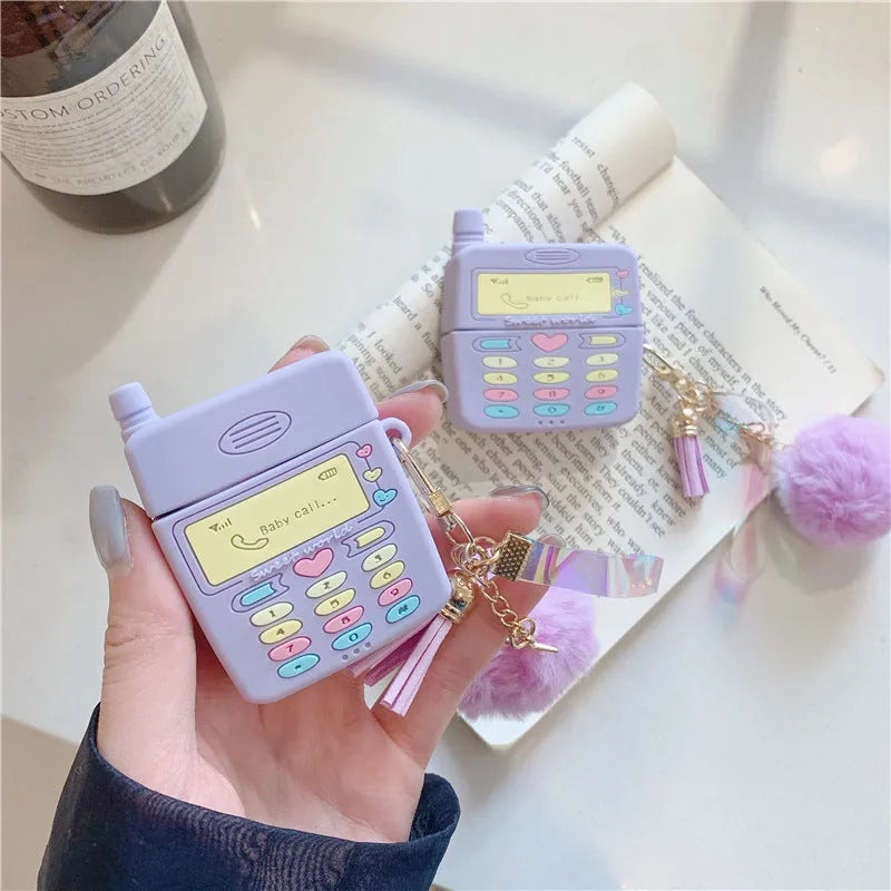 Purple silicone Apple AirPods protective case with attached fur ball pendant on white background