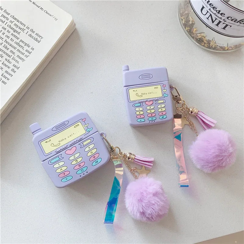 Purple silicone Apple AirPods protective case with attached fur ball pendant on white background