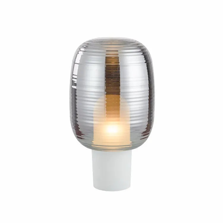 Modern Nordic-style glass table lamp in cognac colour with a push-button switch on a wooden table.
