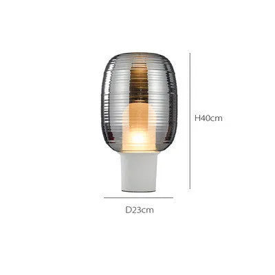 Modern Nordic-style glass table lamp in cognac colour with a push-button switch on a wooden table.