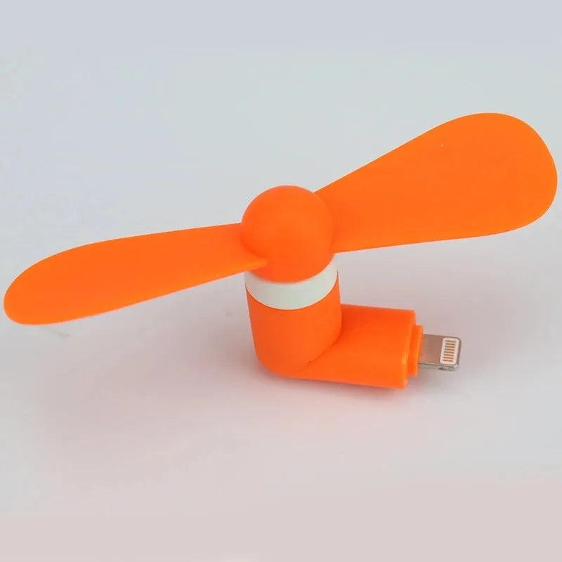 White USB-powered mini personal fan with round plastic blades and a rotary switch, shown next to a mobile phone.