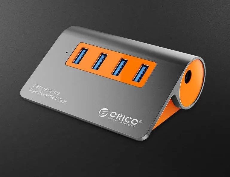 Dark grey aluminium USB hub with four USB 3.1 ports and orange accents, shown with a 100cm data cable.