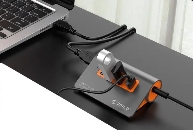 Dark grey aluminium USB hub with four USB 3.1 ports and orange accents, shown with a 100cm data cable.