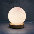 Nordic style USB table lamp with a glass shade shown in one of seven available colours on a bedside table.