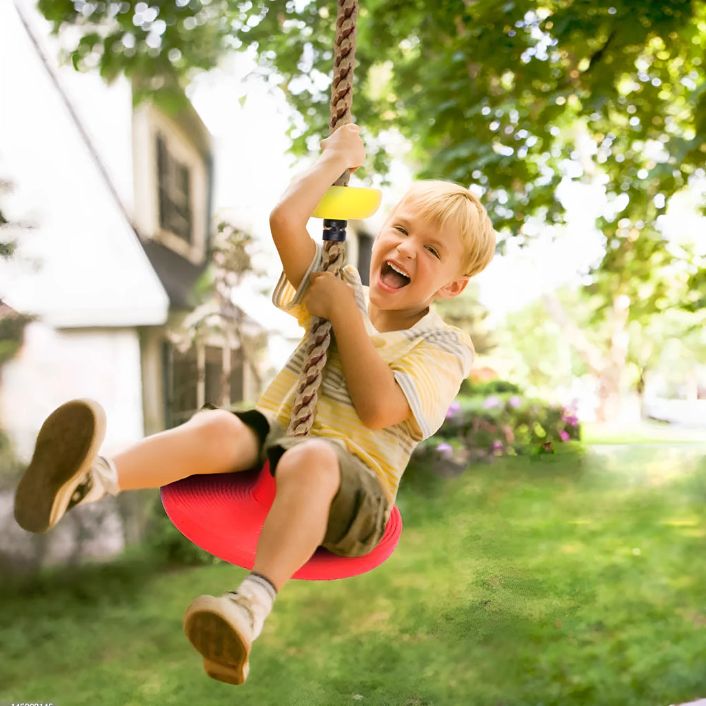 Plastic children's swing set with four colourful platforms on a climbing rope in a backyard