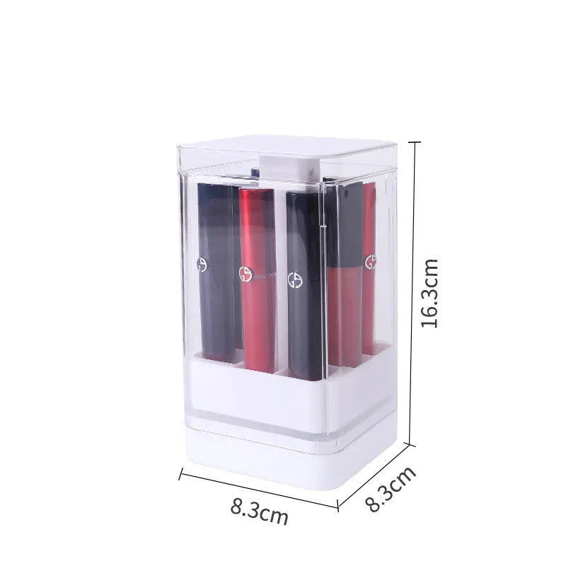 White press-lift lipstick storage box with dust cover on a desktop, showing open 12-grid compartments.
