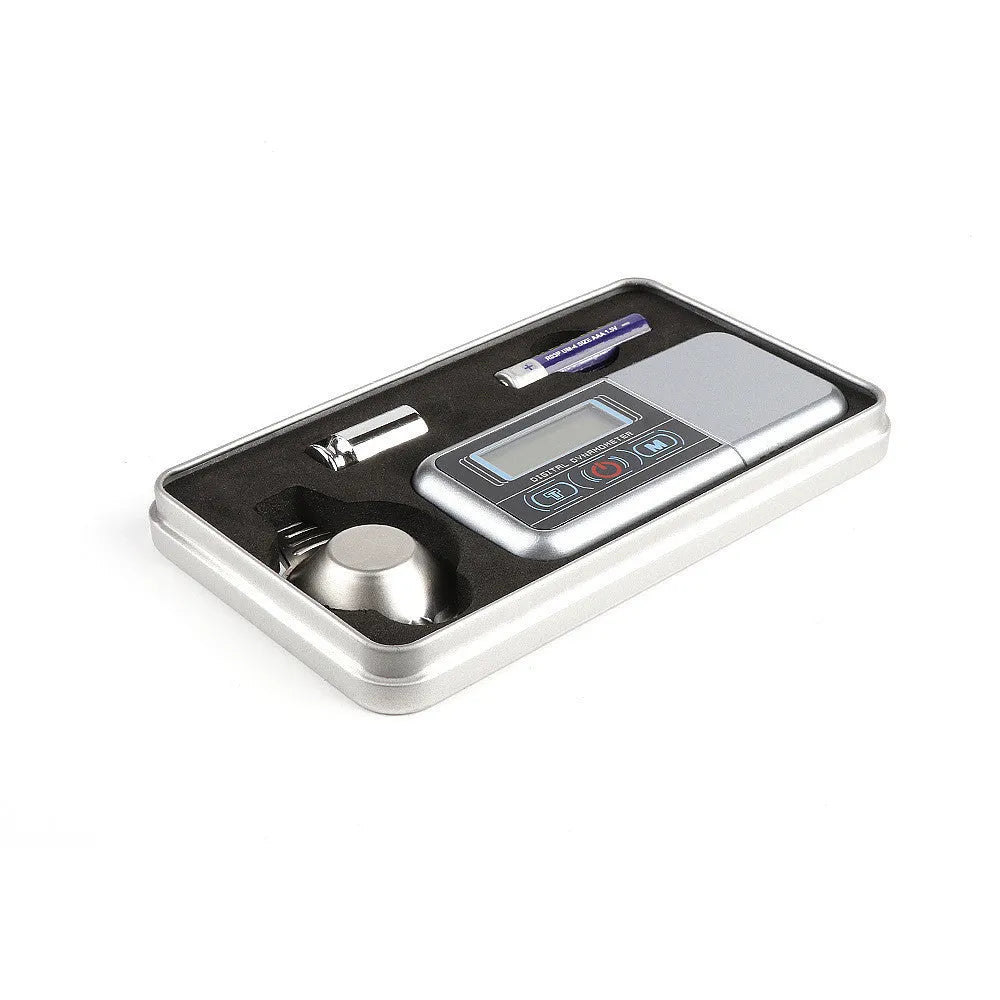 Compact digital electronic scale on a surface, showing a 100g max capacity and 0.005g precision.
