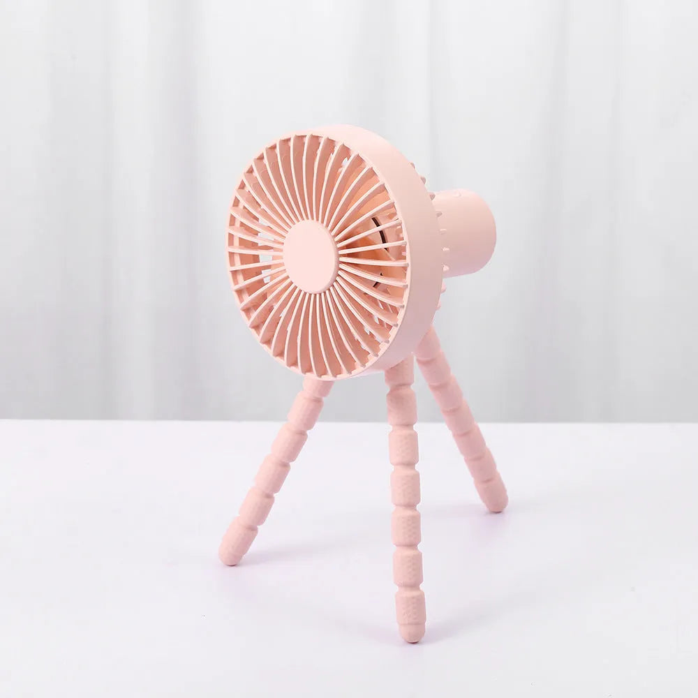 Compact USB desktop fan with flexible black tripod legs and a white fan head on a wooden desk.