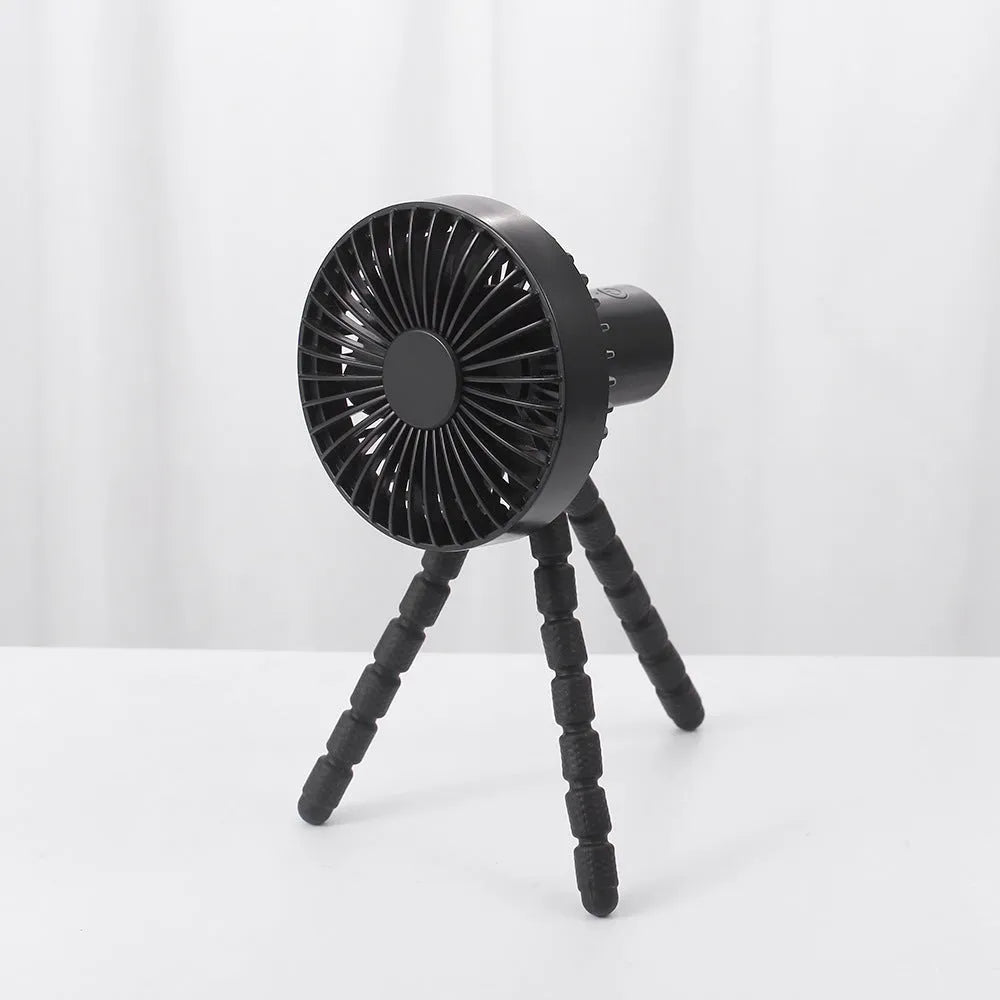 Compact USB desktop fan with flexible black tripod legs and a white fan head on a wooden desk.