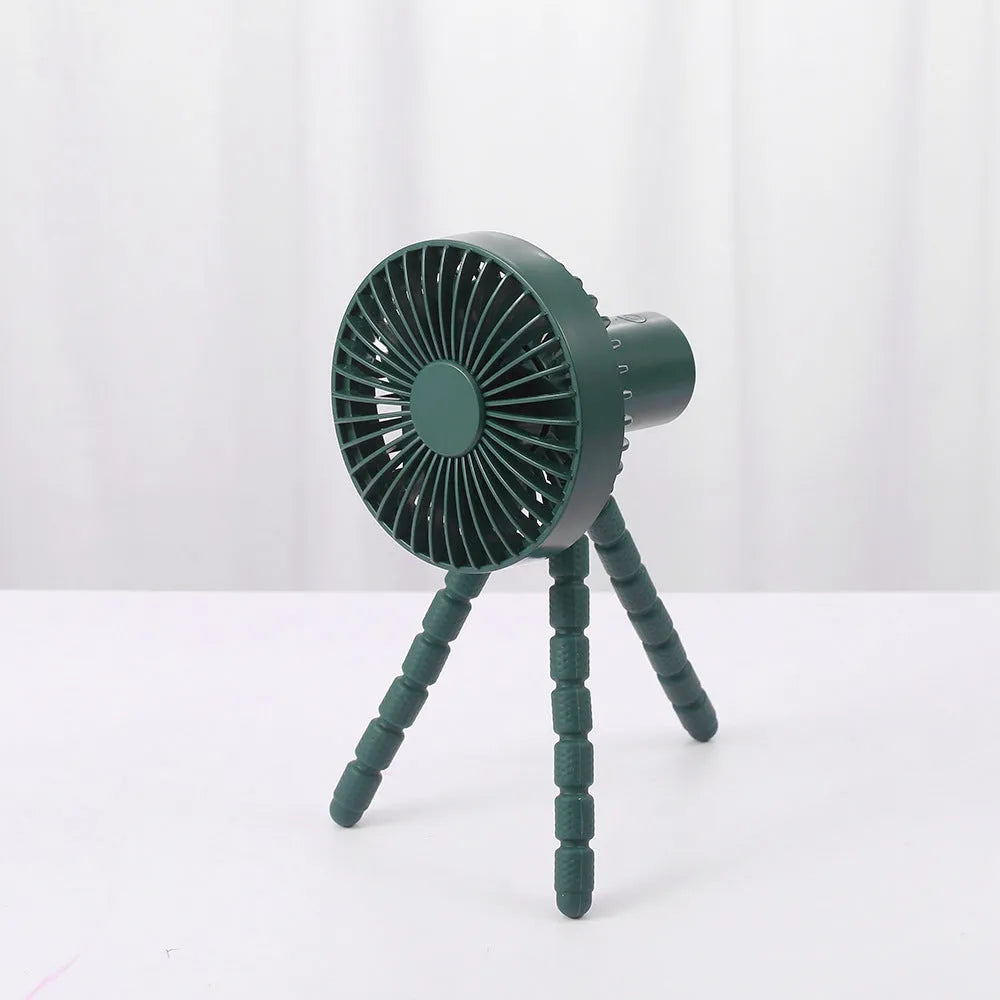 Compact USB desktop fan with flexible black tripod legs and a white fan head on a wooden desk.