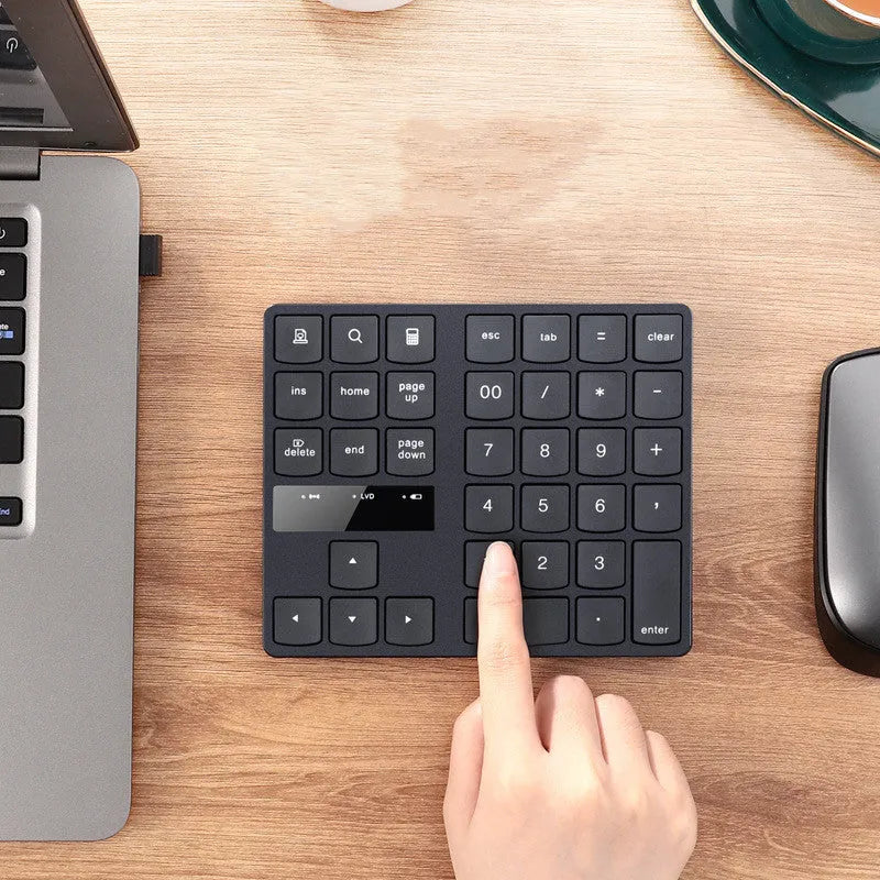 Wireless 35-key numeric keypad in black with USB receiver and charging cable on a desk
