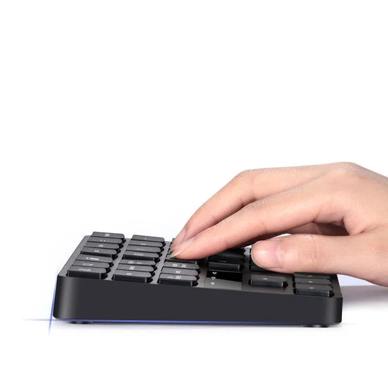Wireless 35-key numeric keypad in black with USB receiver and charging cable on a desk
