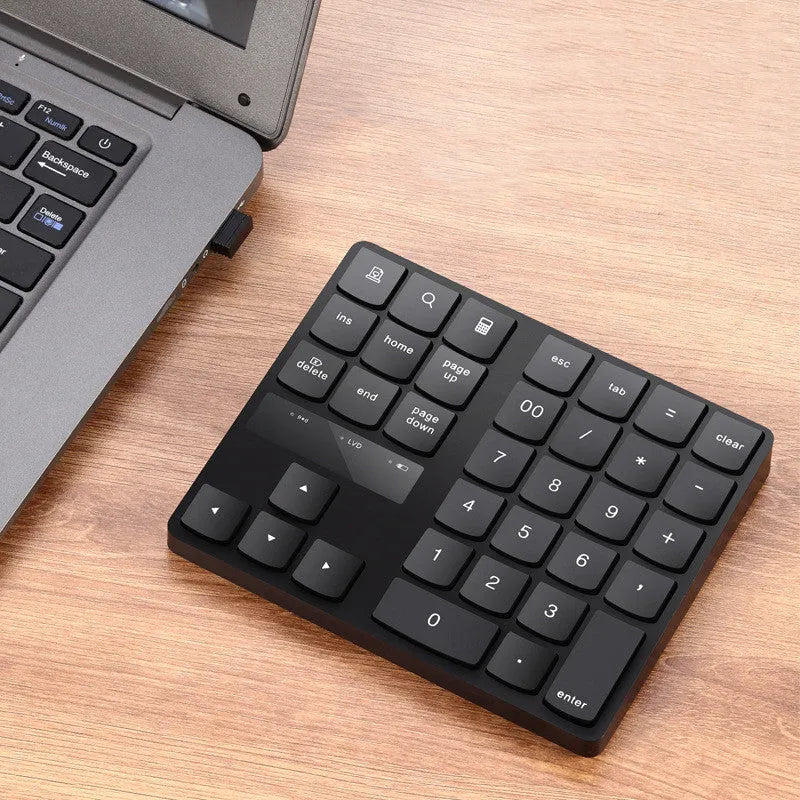 Wireless 35-key numeric keypad in black with USB receiver and charging cable on a desk