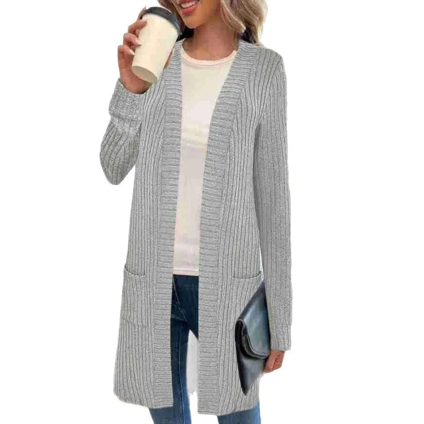 Woman wearing a loose fit, long sleeve, grey knitted cardigan jacket with patch pockets.