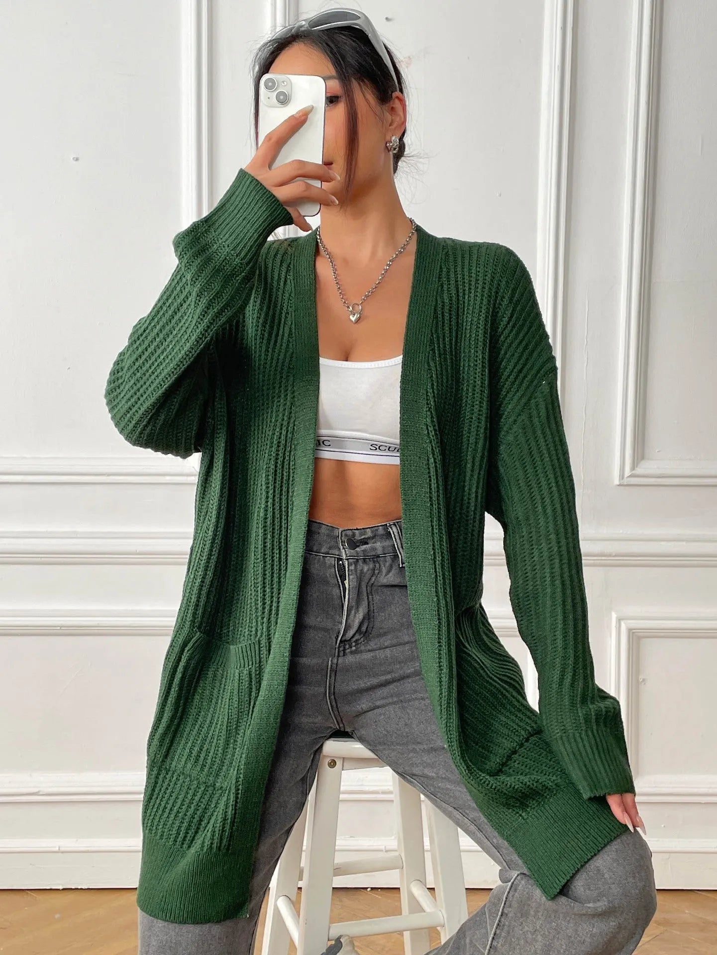 Womans loose fit acrylic cardigan sweater in dark green, showing mid-length and long sleeves.