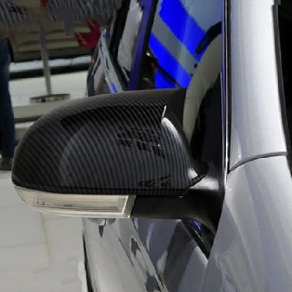 Pair of plastic mirror housings for Volkswagen Sagitar (2006-2011) in black and carbon fibre finishes.