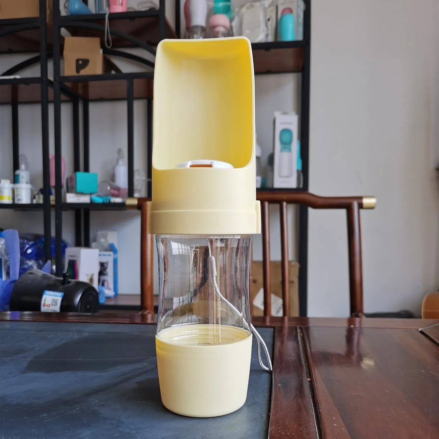 Green portable pet water bottle and food feeder with attached lanyard, showing transparent cup design.