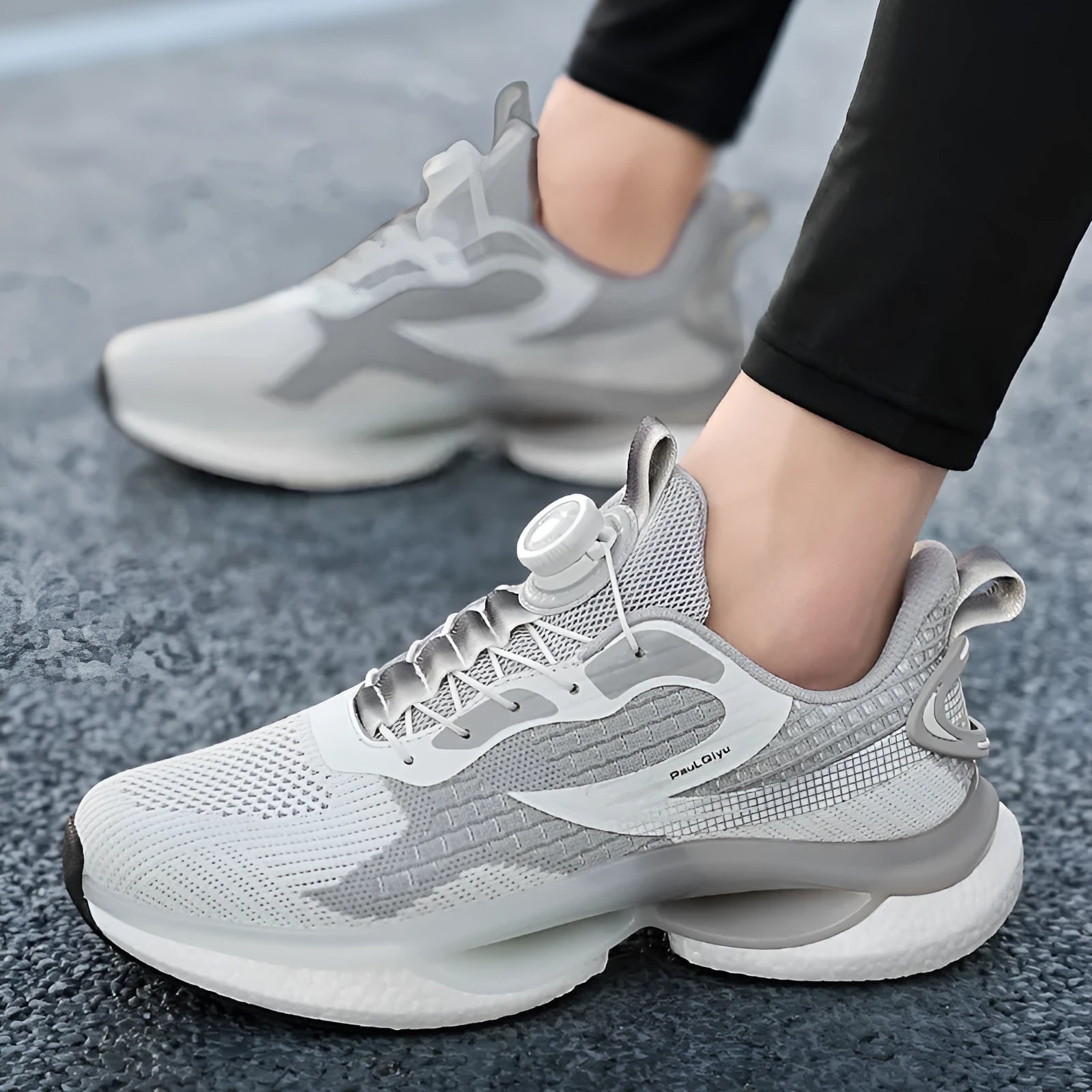 Men's white low-top running shoes with a rotating button buckle and round toe on a gray background.