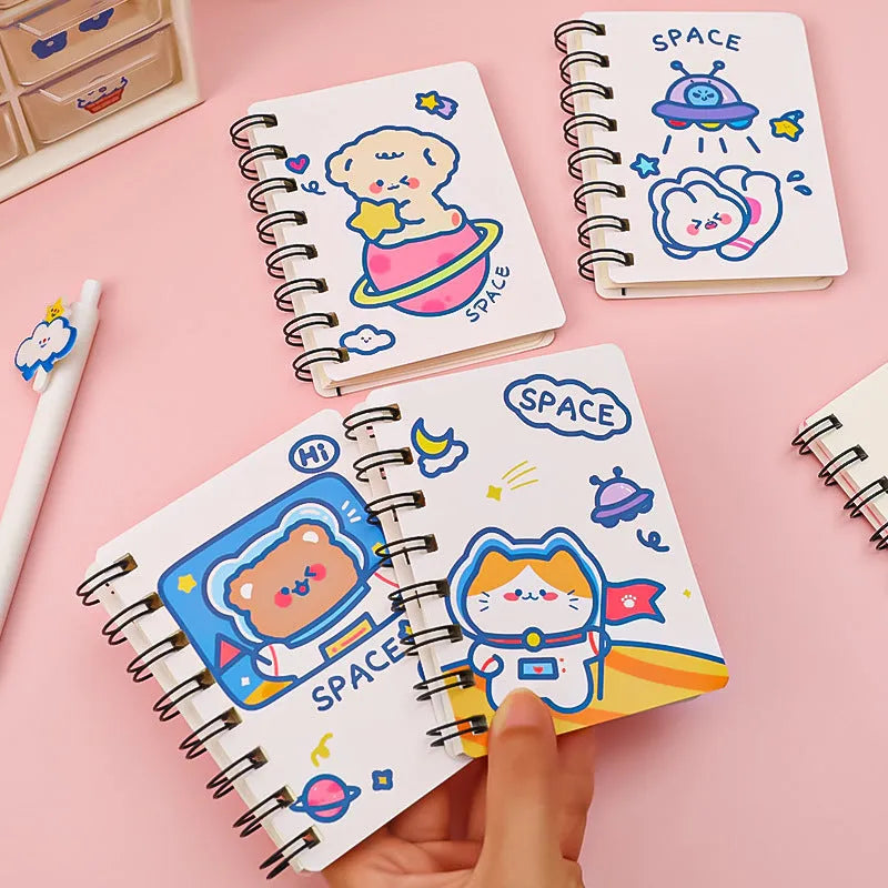 Small astronaut-themed flipper notebook showing one of four cover designs: Astronaut Bear, Planet Teddy, Space Cat, or UFO.