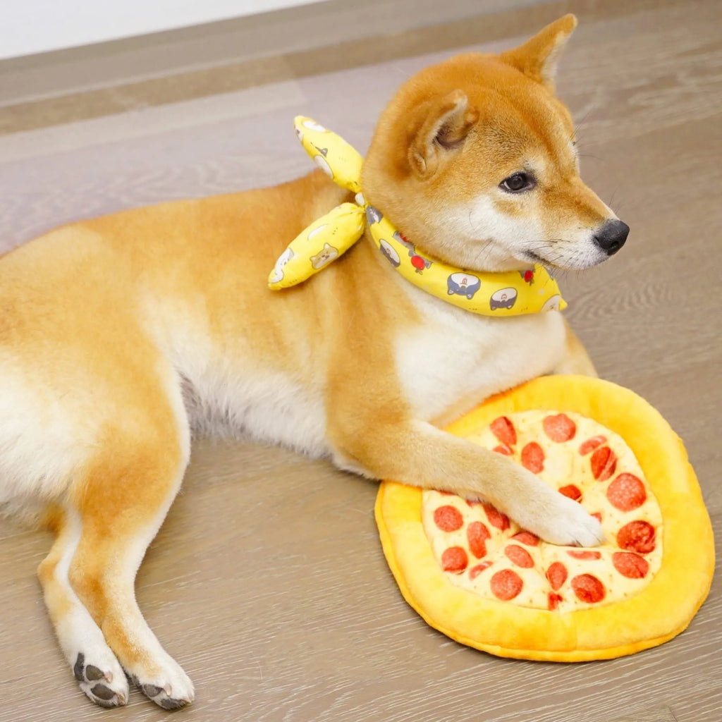 Yellow pizza slice shaped plush squeaky dog chew toy on a white background