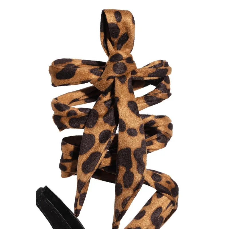 Light brown leopard print women's high heel sandals with cross straps and a tall thin heel.