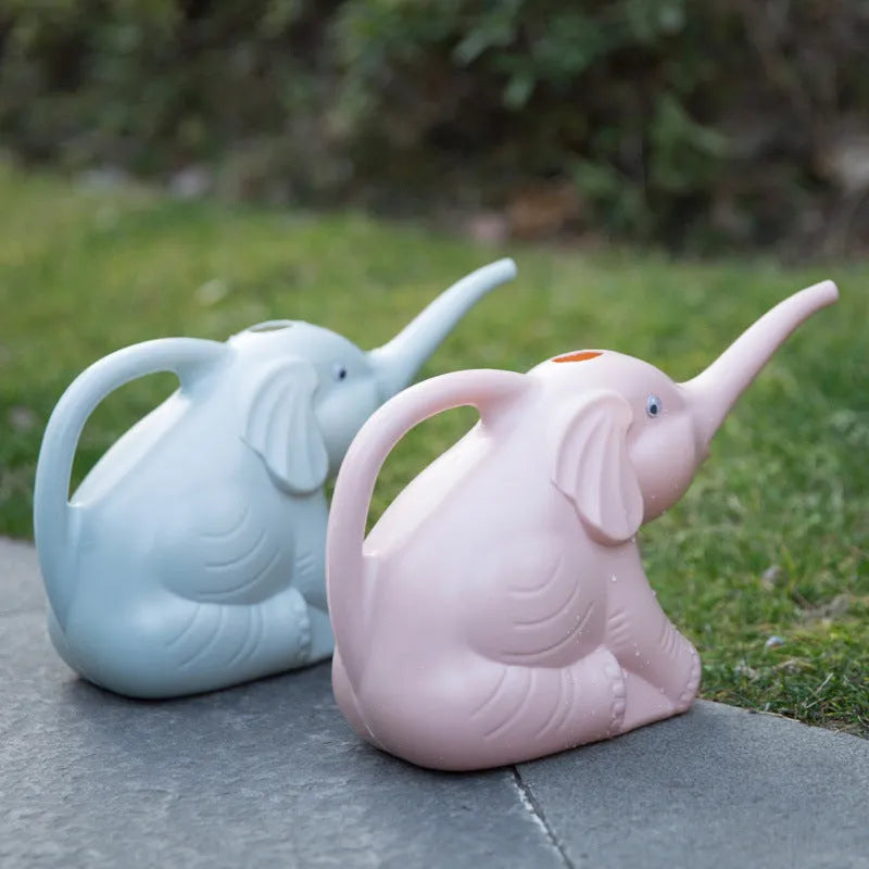 Blue elephant-shaped children's watering can with a long nozzle and baby bottle handle on a table.