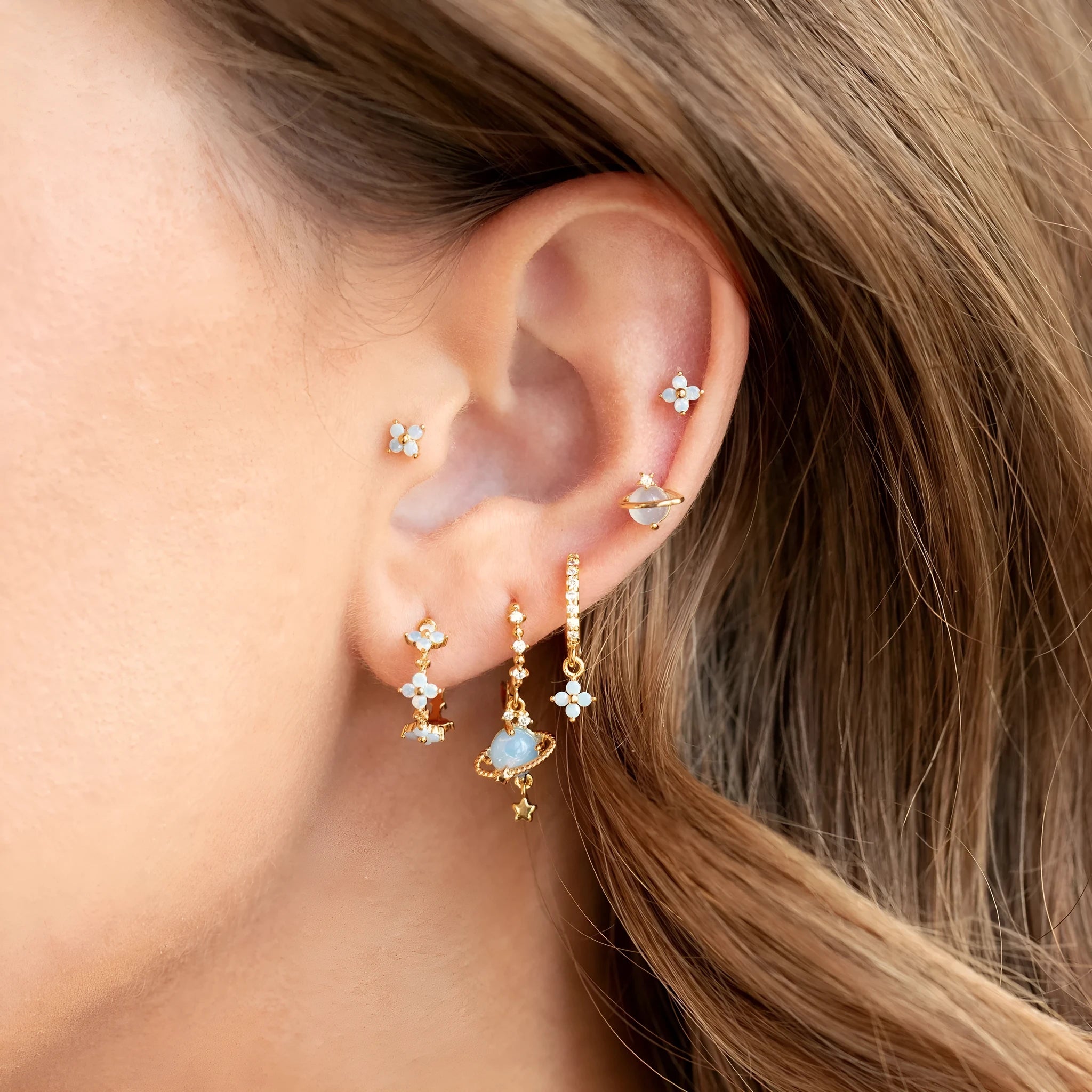 Gold and silver flower shaped stud earrings with zircon mosaic accents on white background