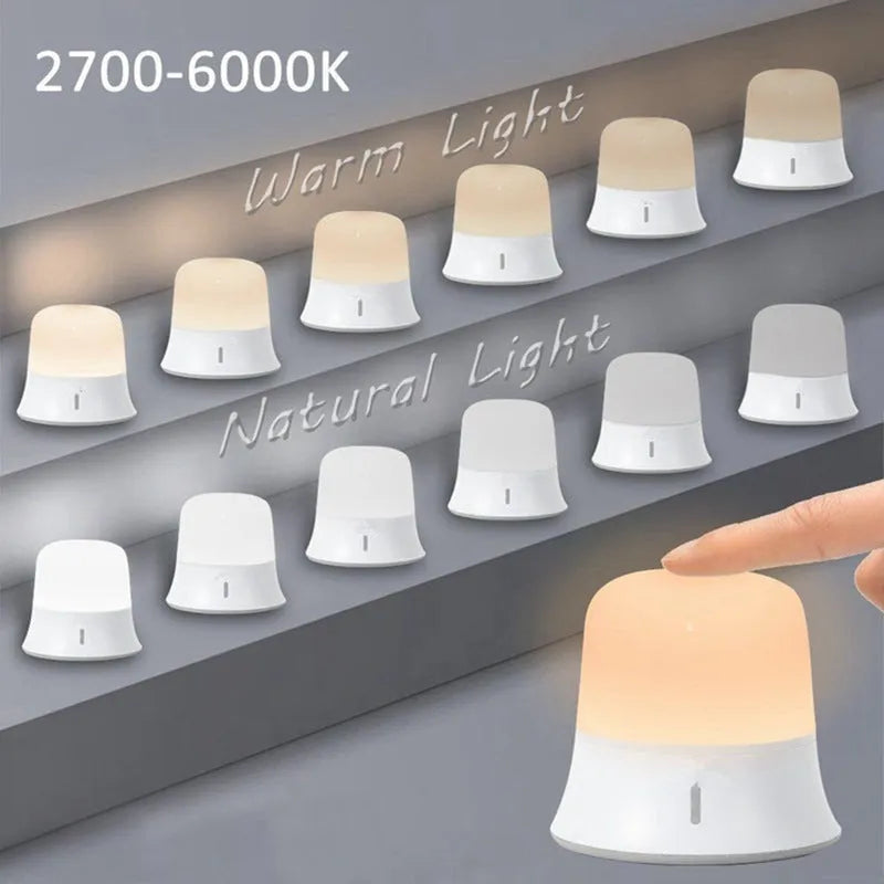 White cylindrical bedside night light with touch controls on a wooden surface.