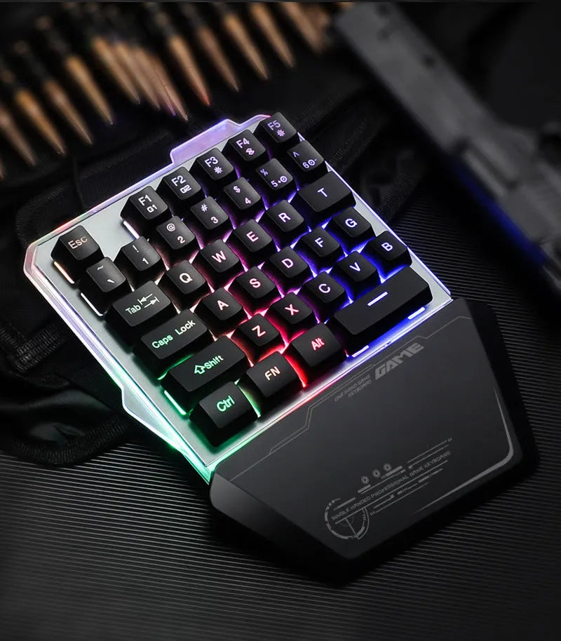 Black one-handed robotic gaming keyboard with RGB backlit keys on a desk.