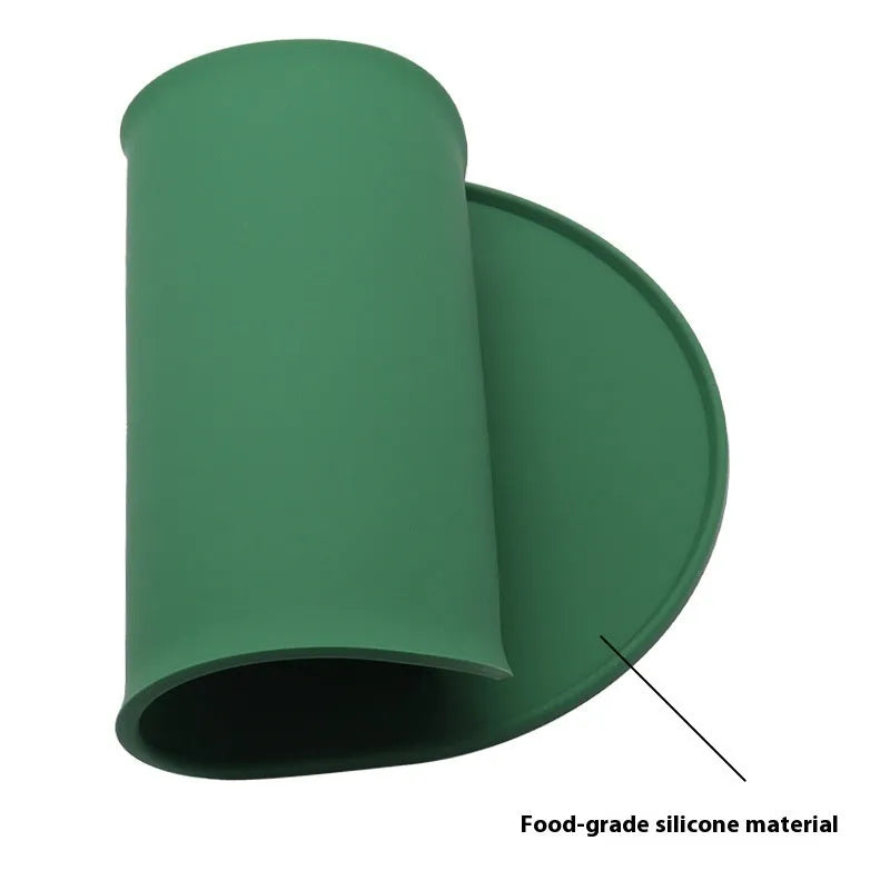 Green silicone cat feeding placemat with food and water bowls on a wooden floor
