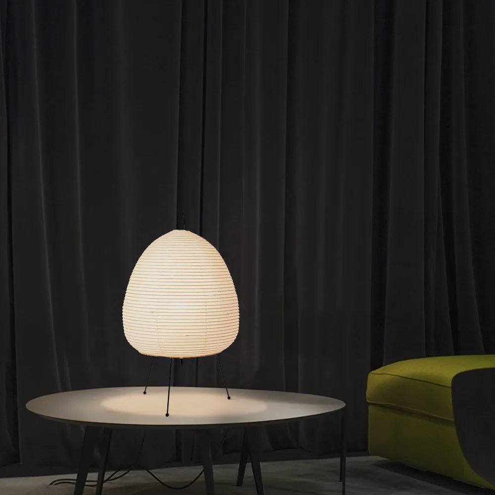 Japanese style handmade rice paper table lamp with an aluminium base on a wooden table.