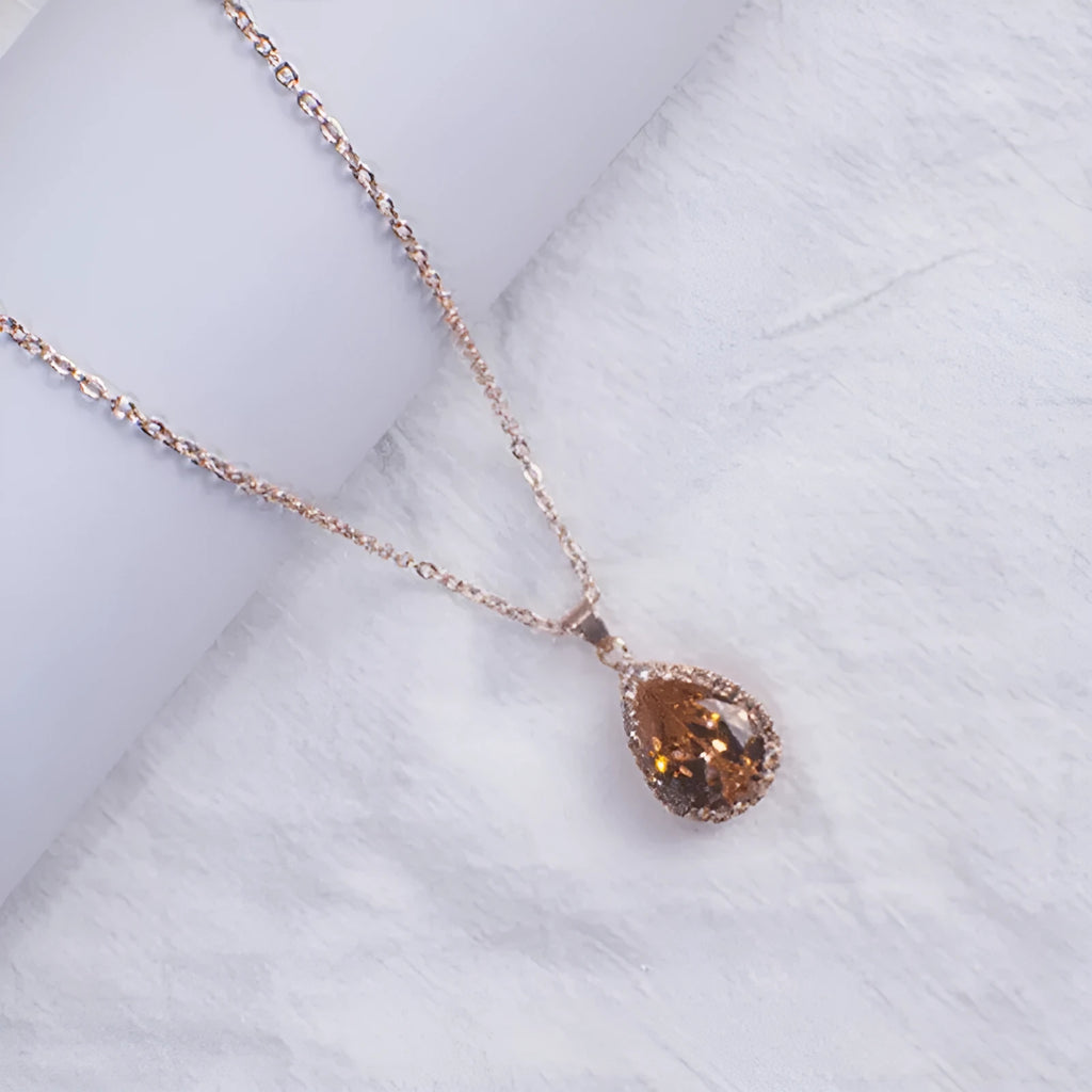 Women's geometric drop shape pendant necklace with rhinestone detail in pink electroplated finish.