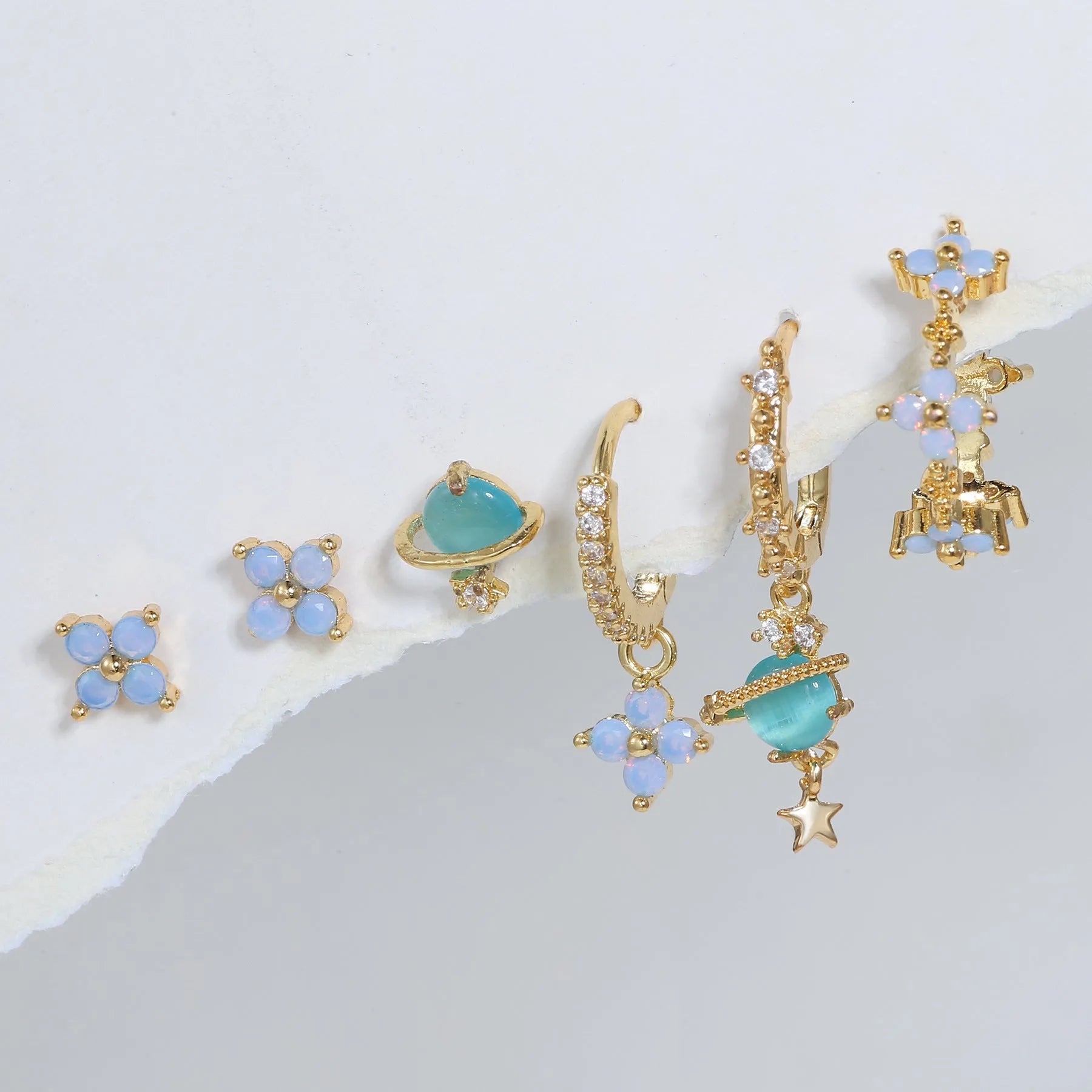 Gold and silver flower shaped stud earrings with zircon mosaic accents on white background