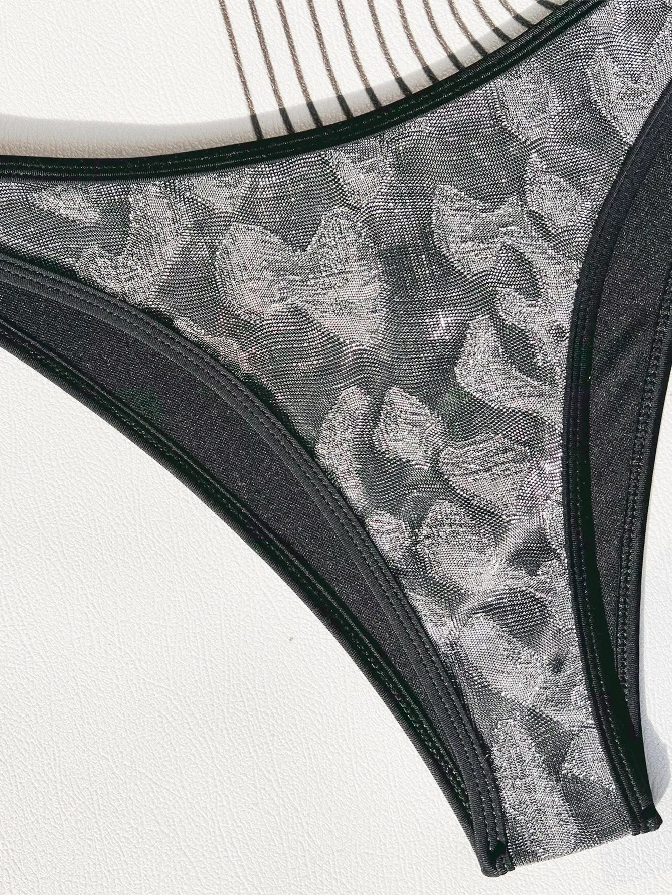 Black women's polyester bikini swimsuit with adjustable straps laid flat.