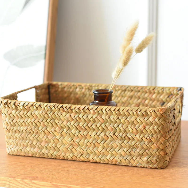 Handmade straw woven rectangular storage basket in natural grass fibre on a shelf