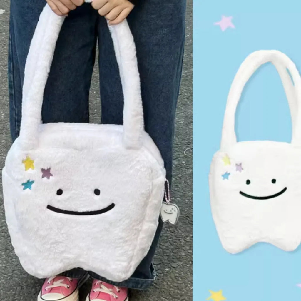 White plush tote bag with tooth decoration and shoulder strap showing zip opening