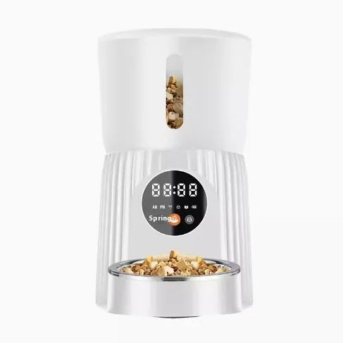 Black automatic pet feeder with digital display and food container on kitchen counter