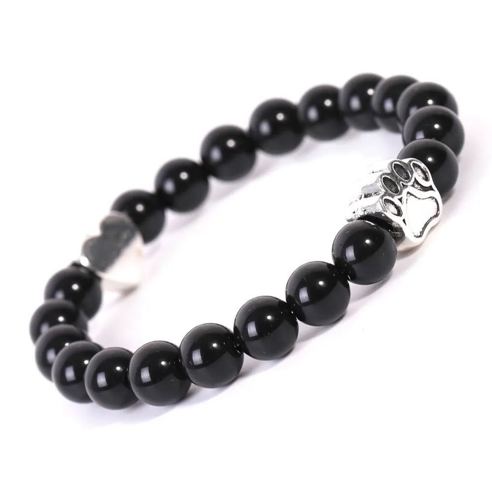 Close-up of a tiger's eye and Indian agate bead bracelet with a central geometric dog's paw charm on a wrist.