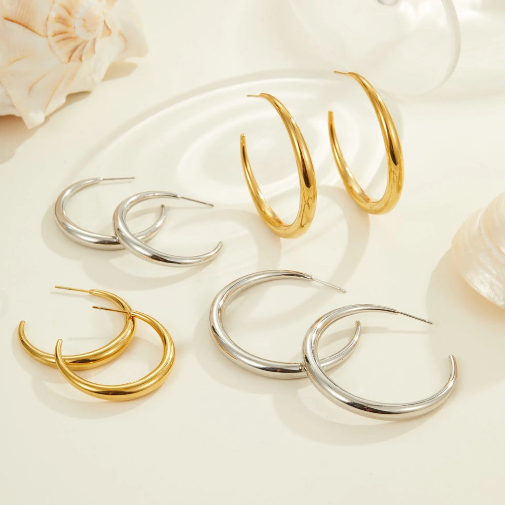 A pair of simple round titanium steel hoop earrings for women, shown in gold and steel finishes.