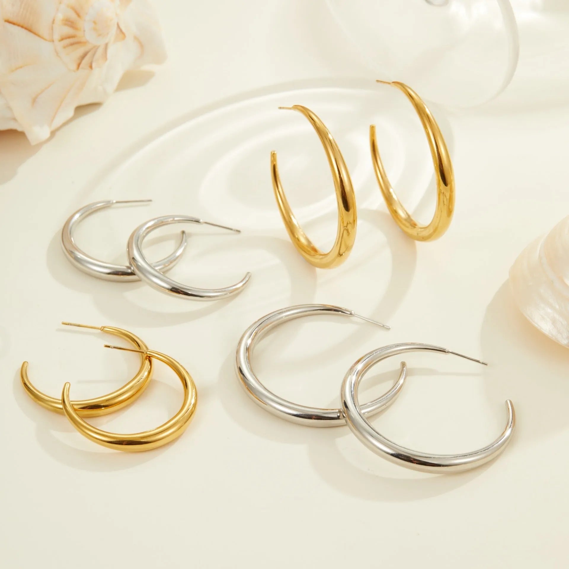 A pair of simple round titanium steel hoop earrings for women, shown in gold and steel finishes.